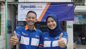 pasangan yang bekerja sebagai agen brilink di daerah tempat tinggalnya sambil berpose mengacungkan ibu jari