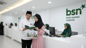 pasangan muda melihat ke arah buku dan memegang gambar rumah impian di kantor bank syariah nasional.